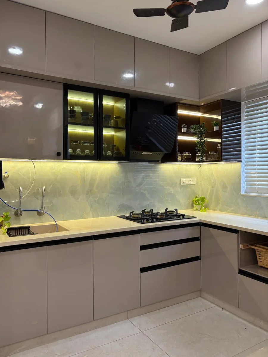 Kitchen set warna abu-abu taupe mengkilap dengan fitur backsplash batu onyx yang menyala dan rak sudut terbuka.