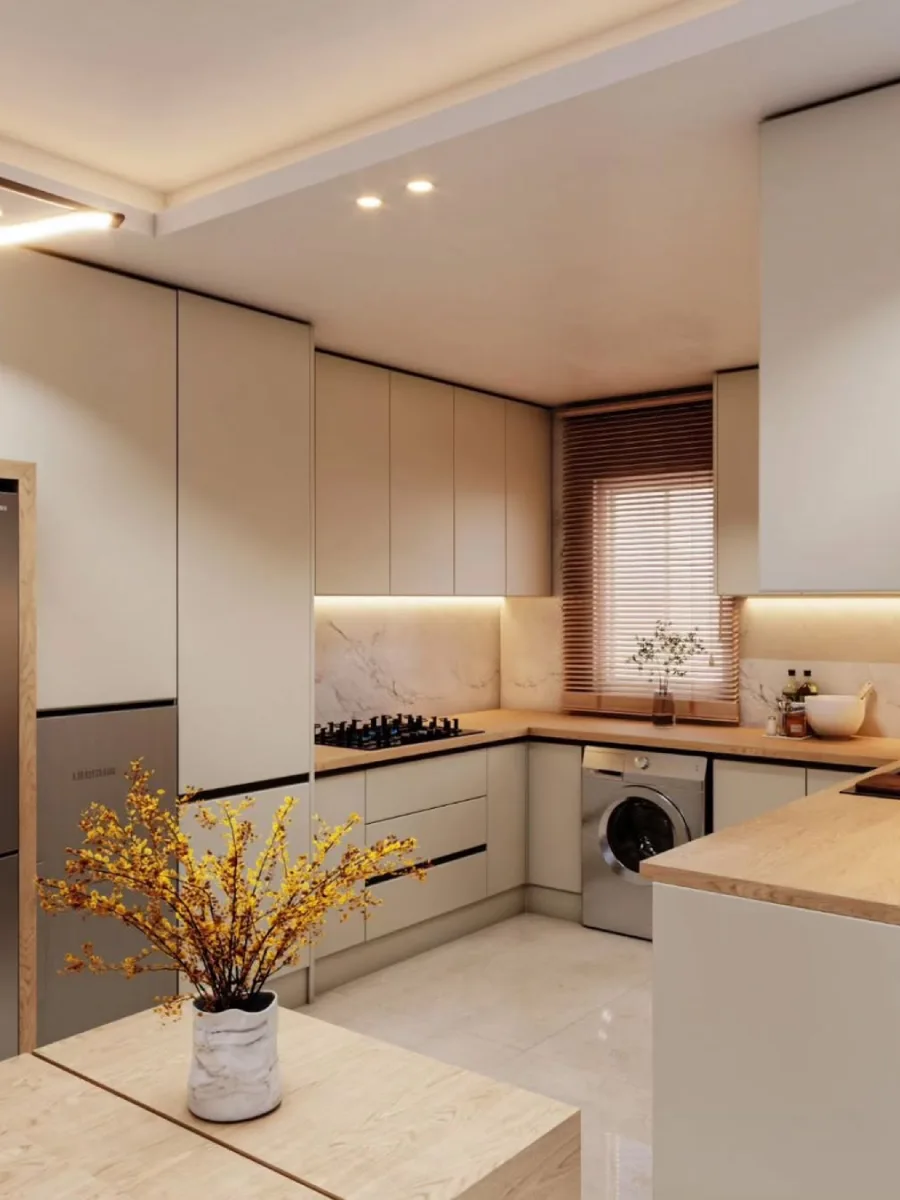 Area memasak dapur modern dekat jendela dengan tirai kayu (venetian blinds), kompor tanam, dan kabinet warna beige lembut.