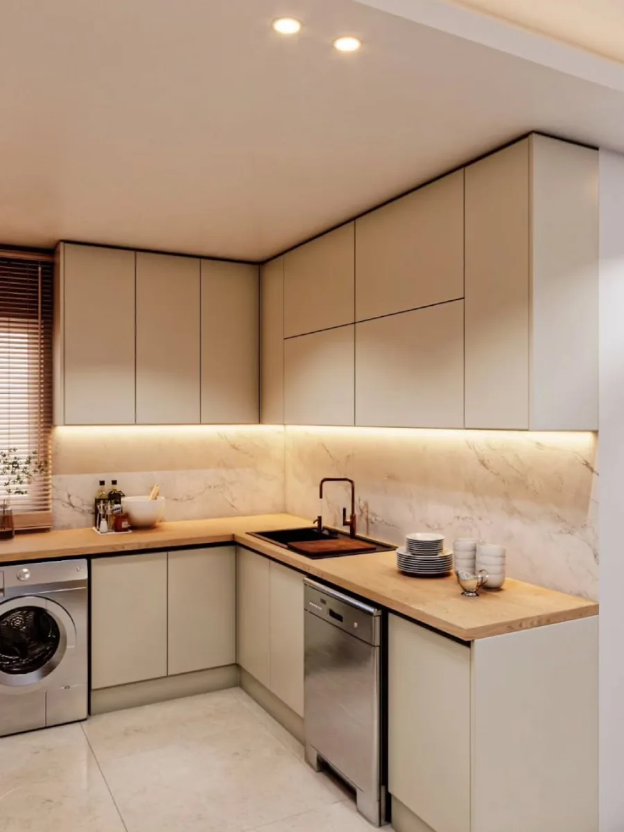 Sudut dapur minimalis fungsional dengan countertop kayu, dinding marmer, dan mesin cuci front loading yang tertanam rapi di bawah meja.