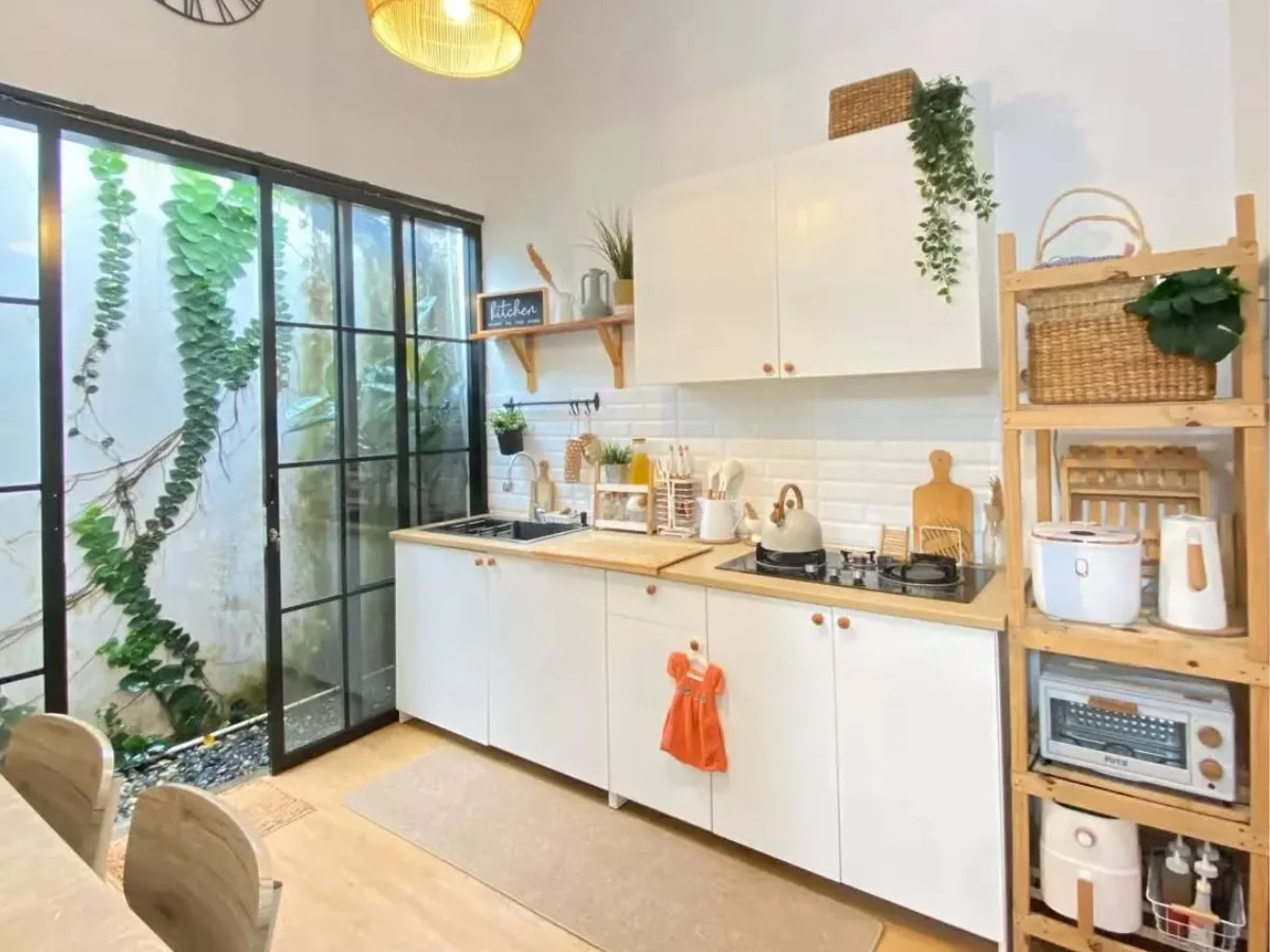 Inspirasi dapur minimalis modern yang menyatu dengan ruang makan (open plan), dilengkapi pintu kaca geser menghadap taman samping untuk pencahayaan alami maksimal.