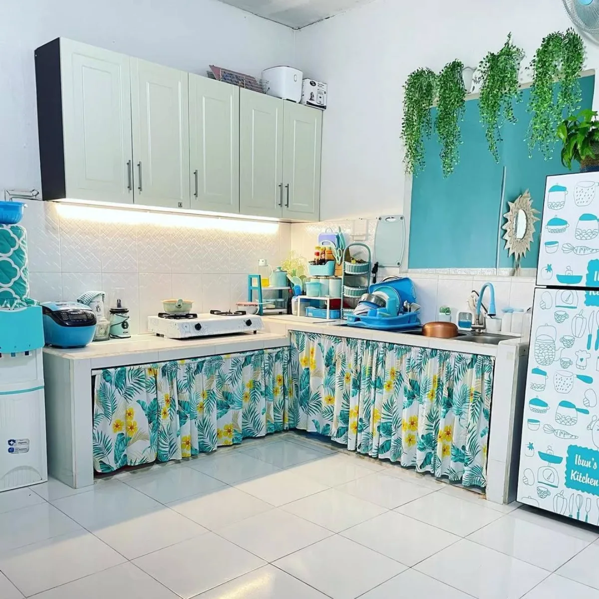 Dekorasi dapur minimalis bernuansa tropis segar dengan dinding hijau toska, hiasan tanaman gantung, dan gorden kolong dapur motif daun.