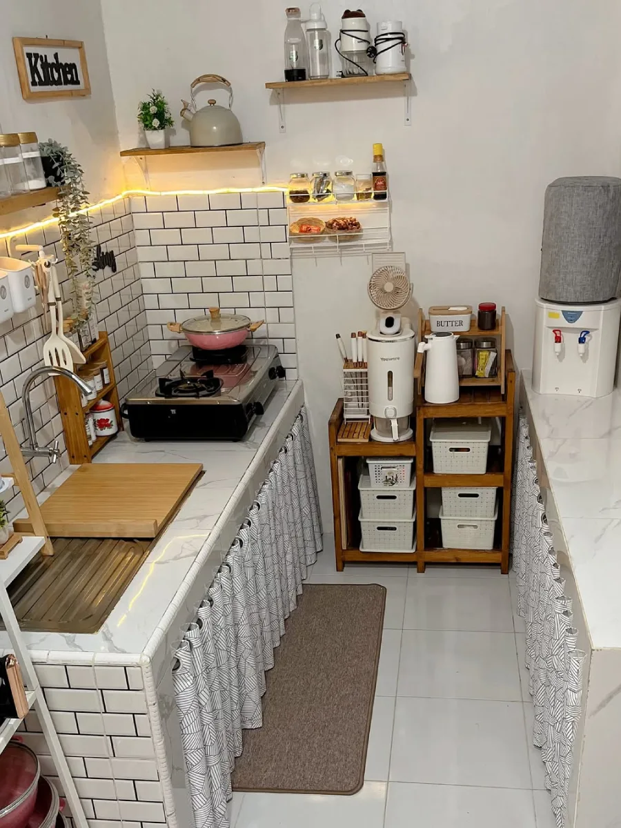 Desain dapur minimalis sederhana dengan keramik dinding subway tile, rak bumbu kayu terbuka, dan penggunaan gorden kolong meja bermotif geometris untuk kesan rapi.