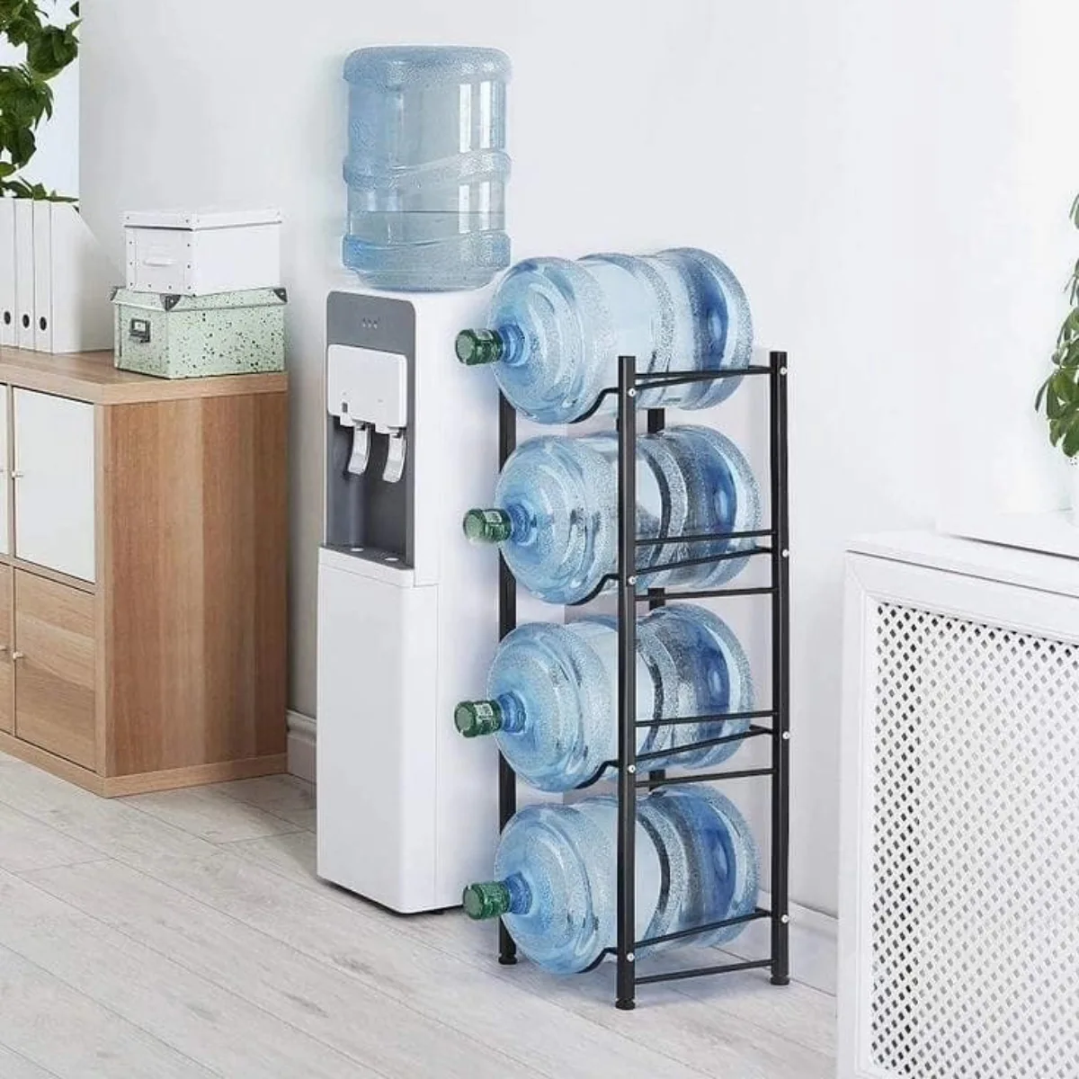 Rak galon air 4 tingkat berbahan metal warna hitam, diletakkan di samping dispenser. Desain kokoh dan hemat ruang.