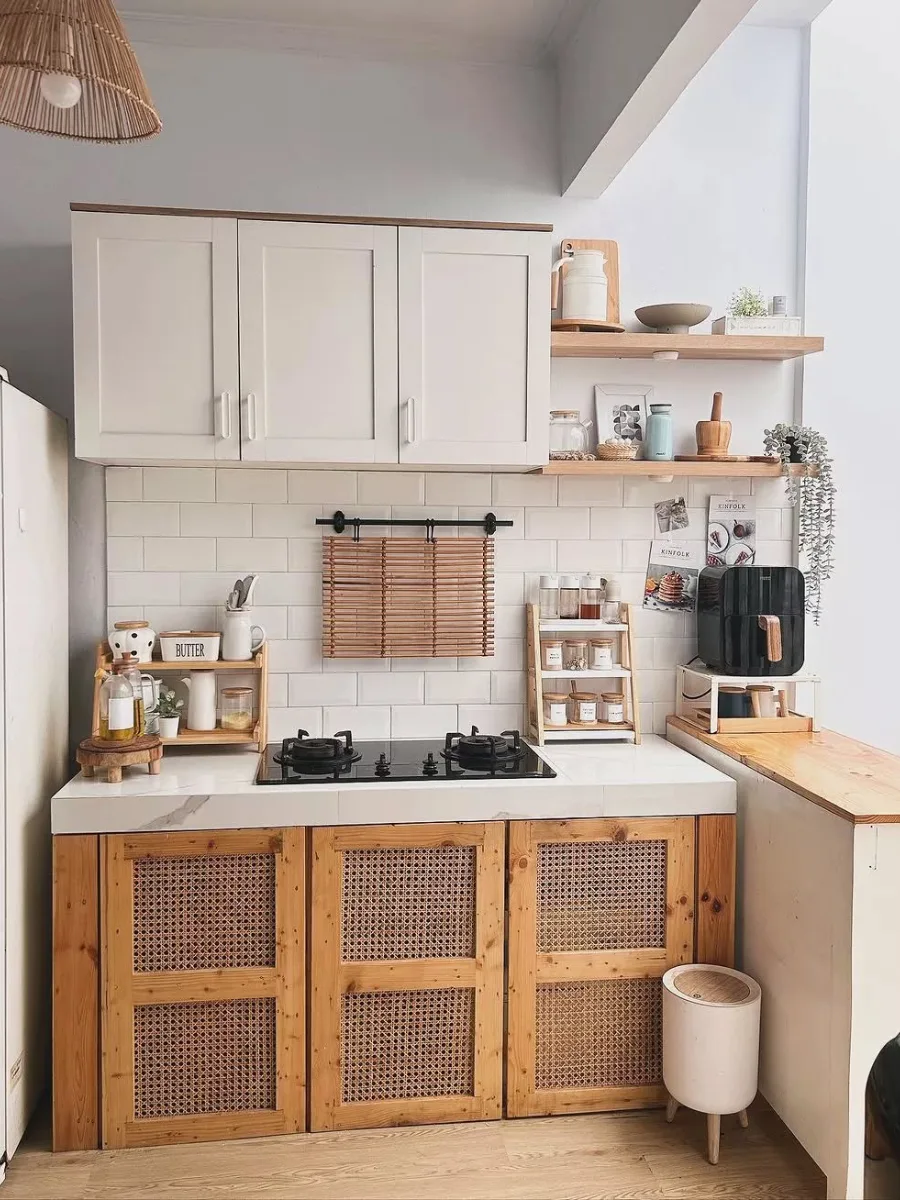 Kitchen set unik dengan pintu kabinet aksen anyaman rotan bergaya Japandi atau Boho, rak bumbu kayu estetik, dan dinding keramik putih minimalis.