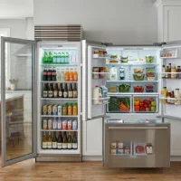 Kulkas premium berkapasitas besar berbahan stainless steel, menampilkan kompartemen minuman berpintu kaca di sisi kiri dan pintu French door di sisi kanan yang terbuka memperlihatkan bahan makanan segar.