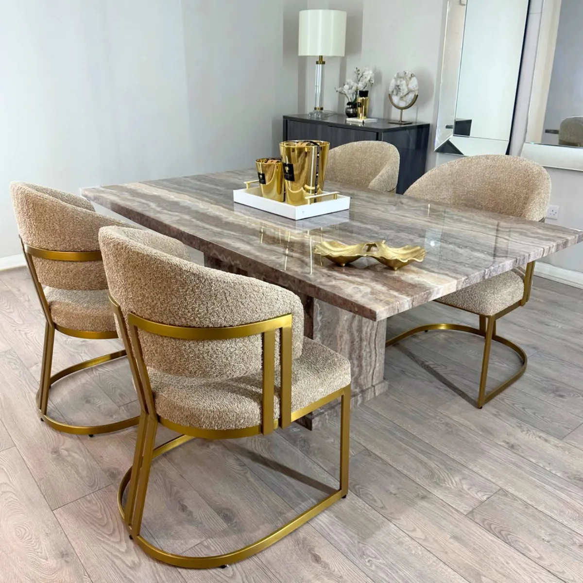 Meja makan minimalis bermotif marmer dengan sentuhan glamour dari empat kursi bertekstur empuk yang memiliki rangka berwarna emas.