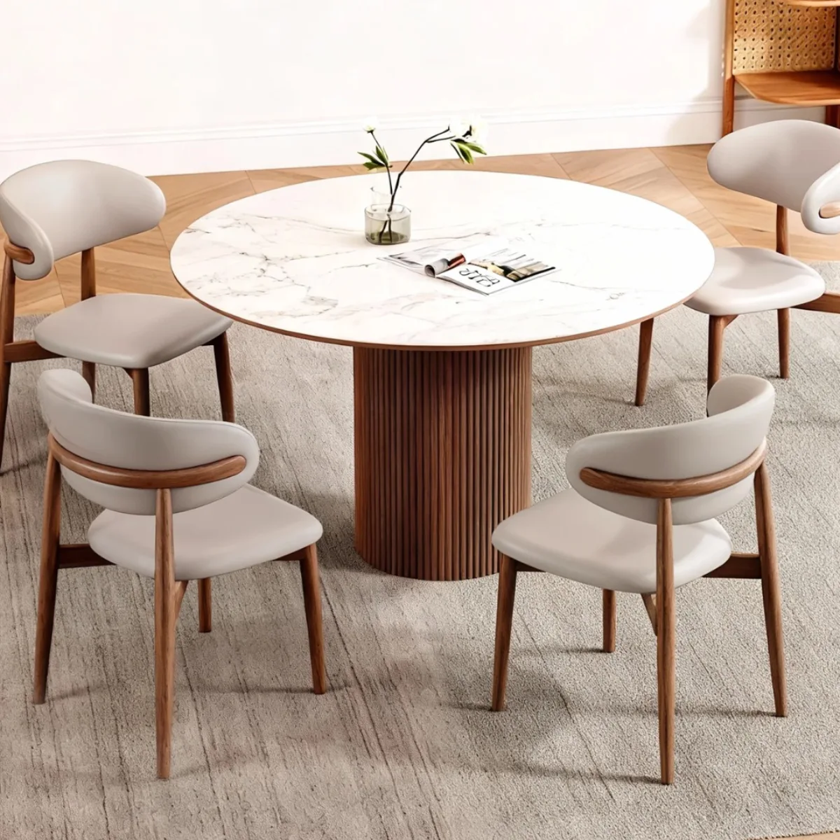 Set meja makan bergaya mid century modern dengan top table marmer putih bundar kaki kayu bergaris dan empat kursi abu-abu melengkung yang ergonomis.