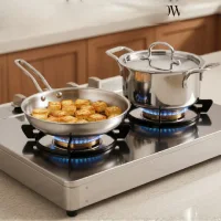 Panci dan wajan stainless steel di atas kompor gas dengan hasil masakan, tampak bersih dan mengilap di dapur modern