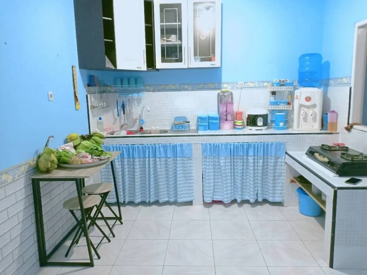 Dapur sederhana dengan dinding cat biru langit cerah, meja makan lipat minimalis, dan tirai kolong dapur bermotif biru putih.