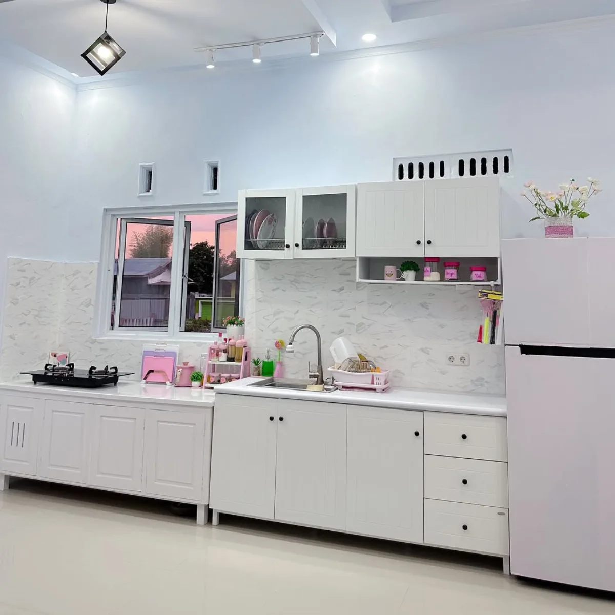 Dapur modern minimalis yang luas dengan cat dinding warna ice blue (biru es) yang sangat muda, kabinet putih bersih, dan pencahayaan lampu gantung geometris.