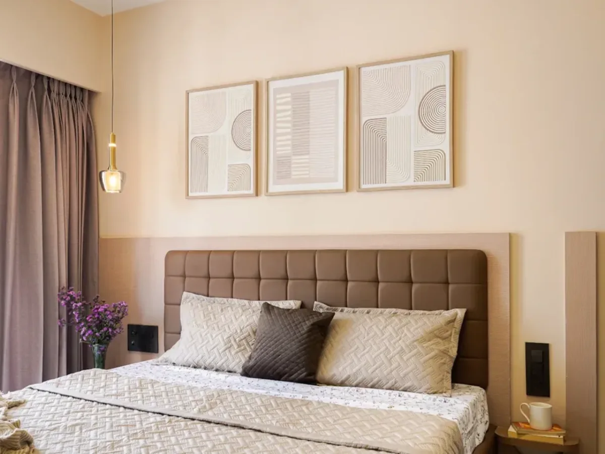 Kamar tidur bernuansa earth tone dengan cat warna krem (beige) monokrom, hiasan dinding bertekstur, dan desain interior gaya Japandi.