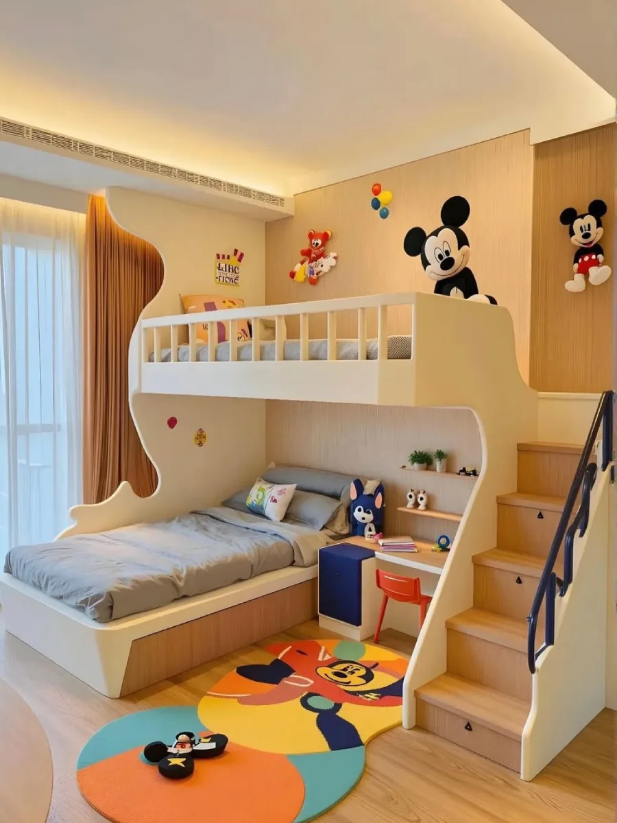 Interior kamar tidur anak minimalis dan modern dengan tempat tidur susun putih terintegrasi, tangga kayu dengan pagar hitam, area belajar kecil, mural dinding Mickey Mouse yang gembira, dan karpet bundar wajah Mickey Mouse yang berwarna-warni.