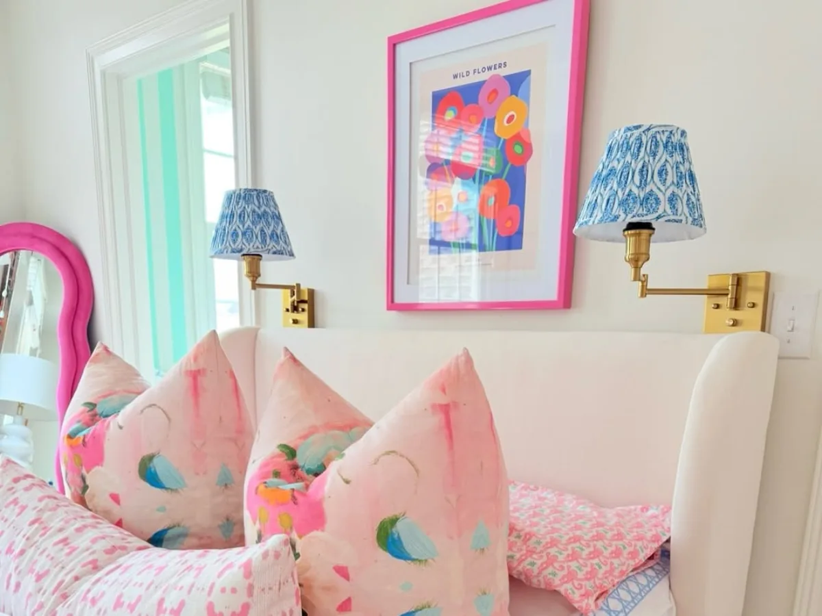 Kamar anak perempuan dengan dekorasi warna pink cerah, bantal motif abstrak, dan lampu dinding biru bermotif etnik.
