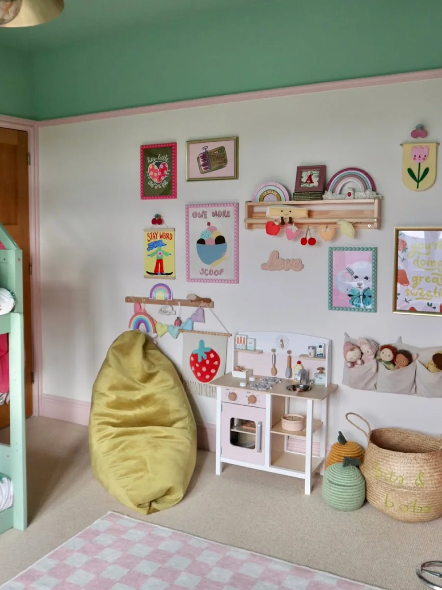 Dinding hijau pastel dengan poster bertema matahari dan pelangi.