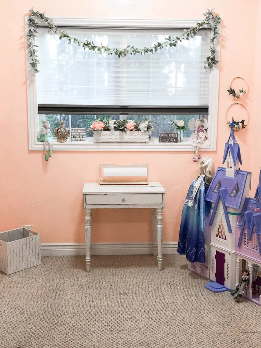 Dinding kamar anak dengan wallpaper bunga kecil dan rak buku kayu.