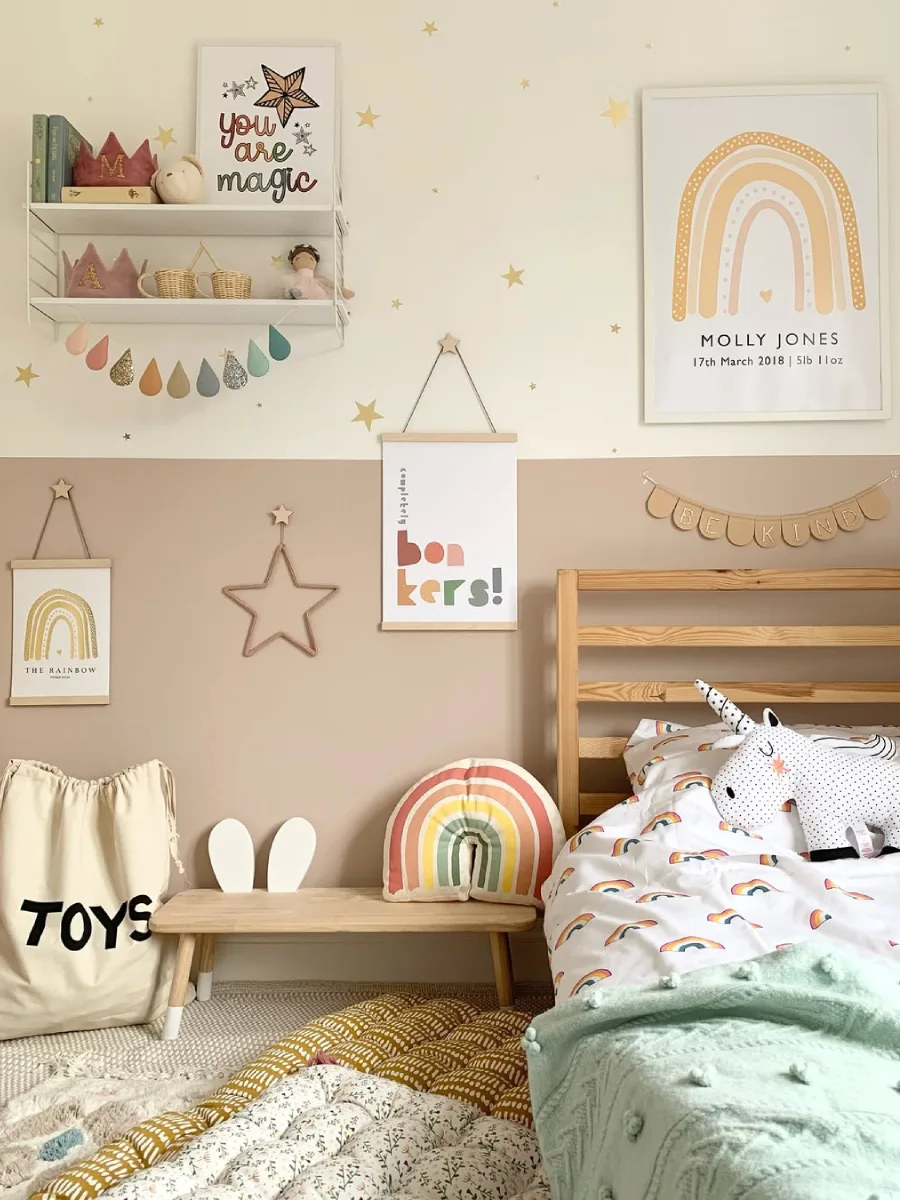 Tempat tidur anak dengan sprei motif pelangi dan dekorasi bintang emas.