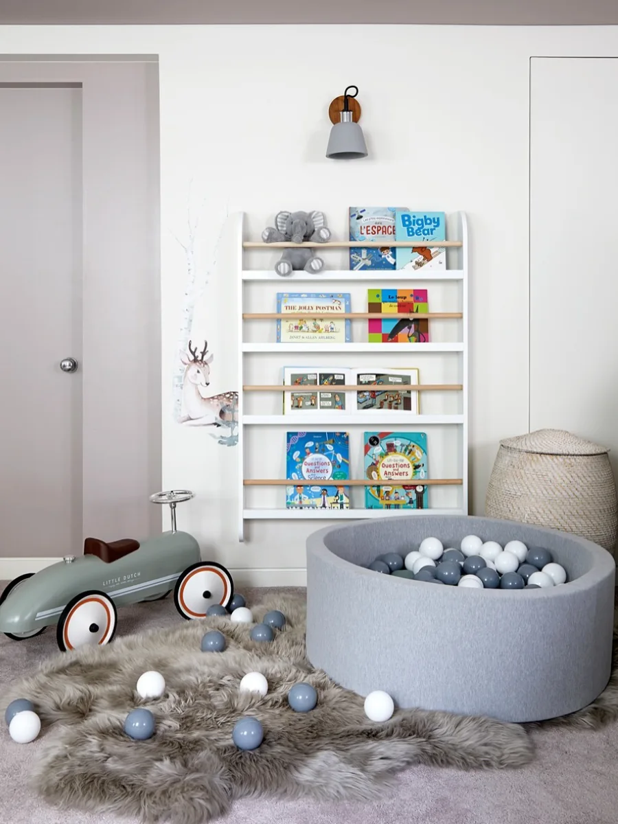 Sudut kamar anak dengan dekorasi unicorn dan rak mainan gantung.