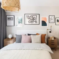 gallery wall kamar tidur minimalis dengan bingkai hitam putih, dekorasi dinding di atas tempat tidur, kombinasi bantal warna netral dan furnitur kayu terang