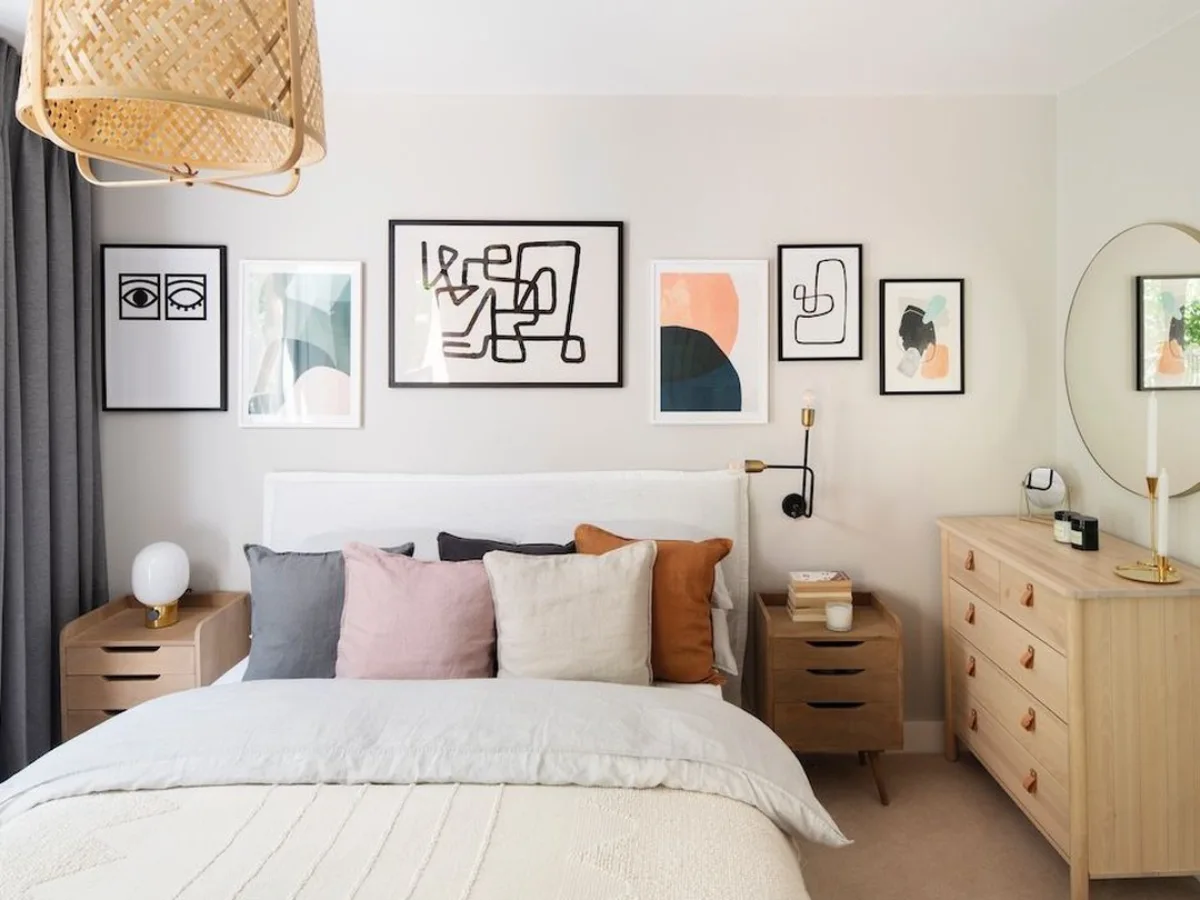 gallery wall kamar tidur minimalis dengan bingkai hitam putih, dekorasi dinding di atas tempat tidur, kombinasi bantal warna netral dan furnitur kayu terang