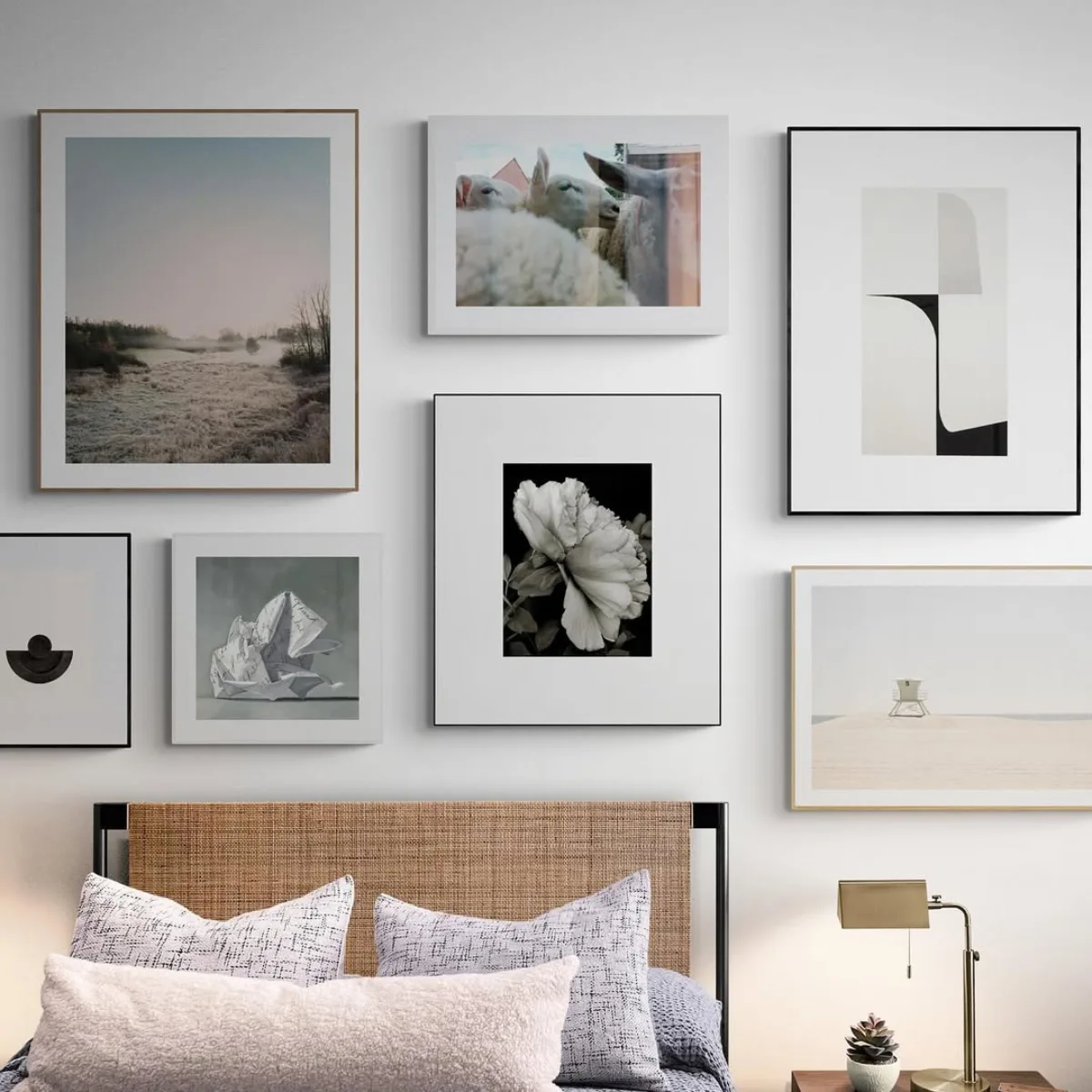 Susunan bingkai foto hitam putih pemandangan dan seni abstrak di dinding atas kasur kamar tidur bernuansa modern