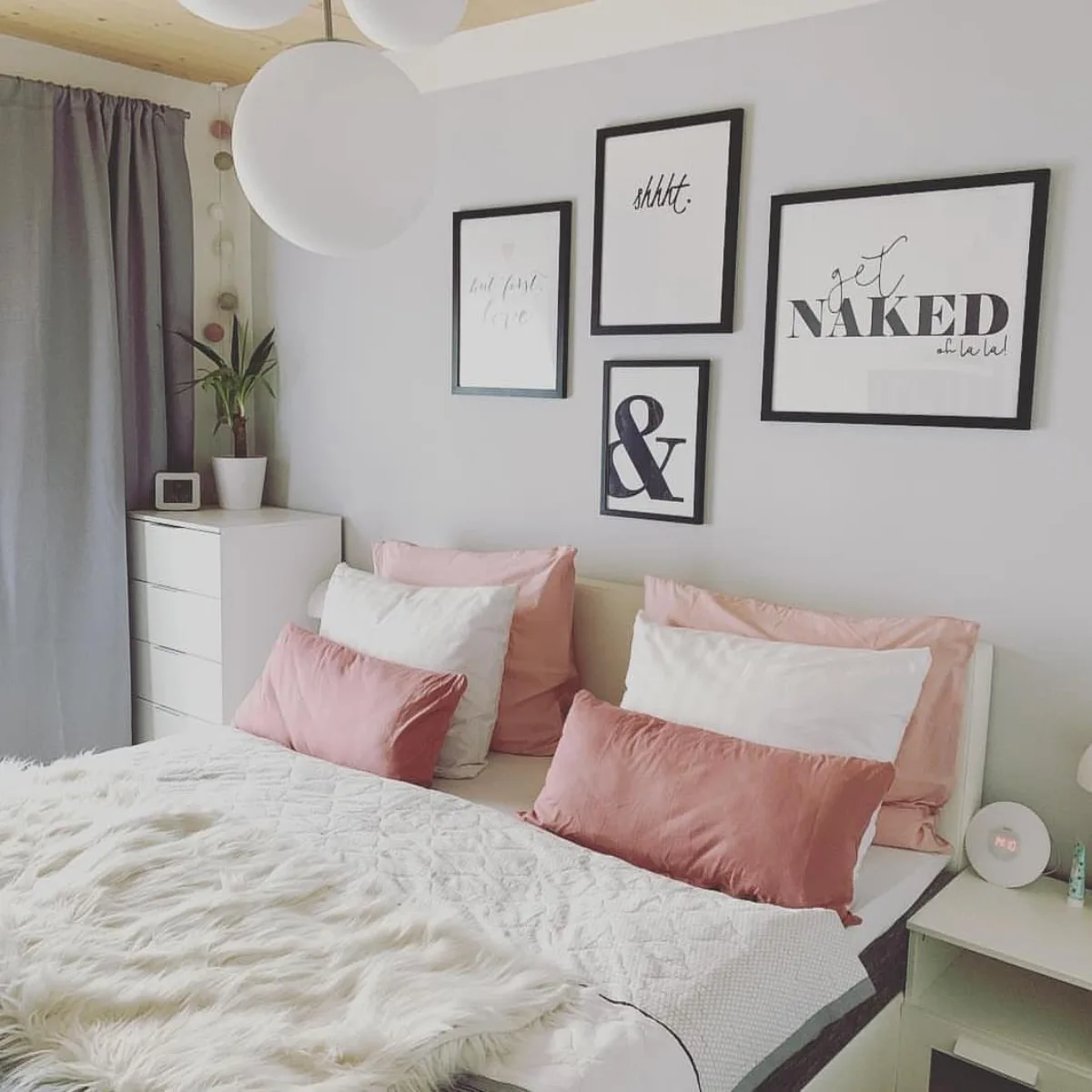 Gallery wall dengan bingkai hitam berisi kutipan tipografi di dinding putih atas kasur dengan bantal bernuansa pink