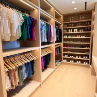 Ruangan lemari pakaian walk in closet kayu berdesain terbuka tanpa pintu dengan susunan rak sepatu dan area gantung pakaian