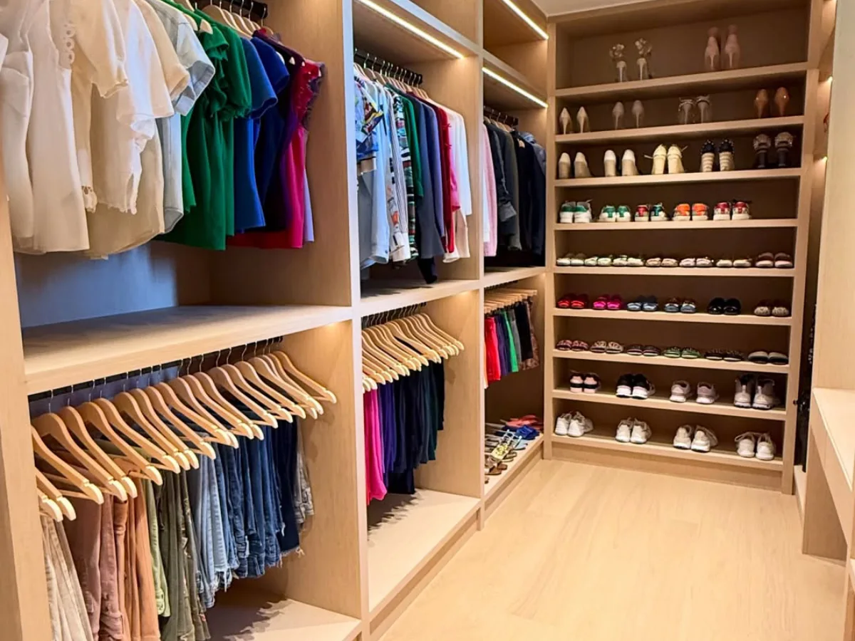 Ruangan lemari pakaian walk in closet kayu berdesain terbuka tanpa pintu dengan susunan rak sepatu dan area gantung pakaian