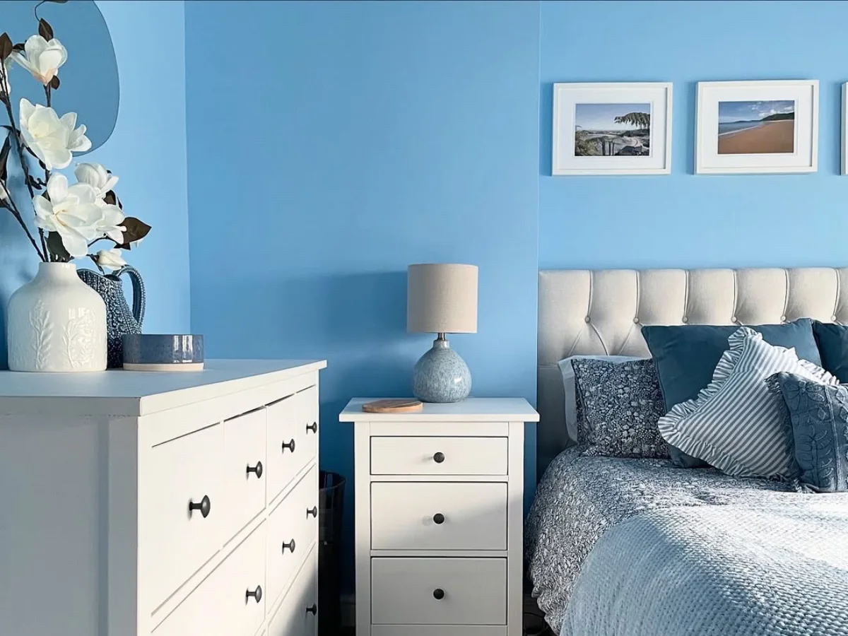 Kamar tidur dengan warna cat biru lembut yang bagus, dipadukan furnitur putih dan nuansa rapi.