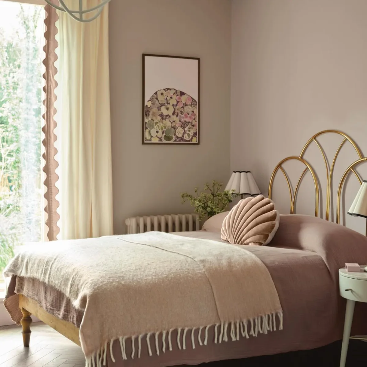 Dekorasi kamar tidur feminin vintage dengan cat dinding warna dusty pink pastel, headboard besi warna emas bentuk kerang, dan gorden dengan detail scallop.