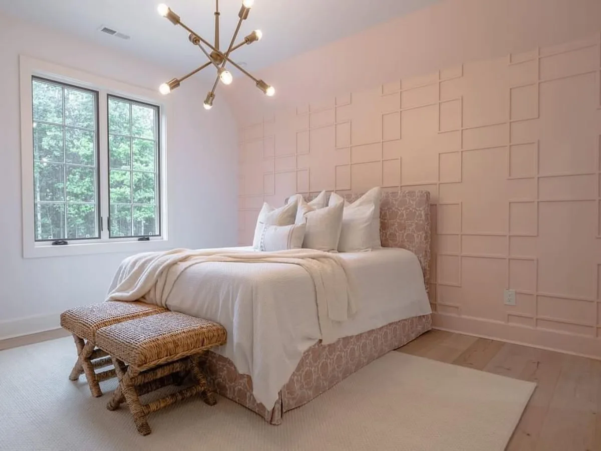 Kamar tidur dengan dinding aksen panel geometris berwarna pink salem, dipadukan dengan lantai kayu terang dan lampu gantung sputnik modern.