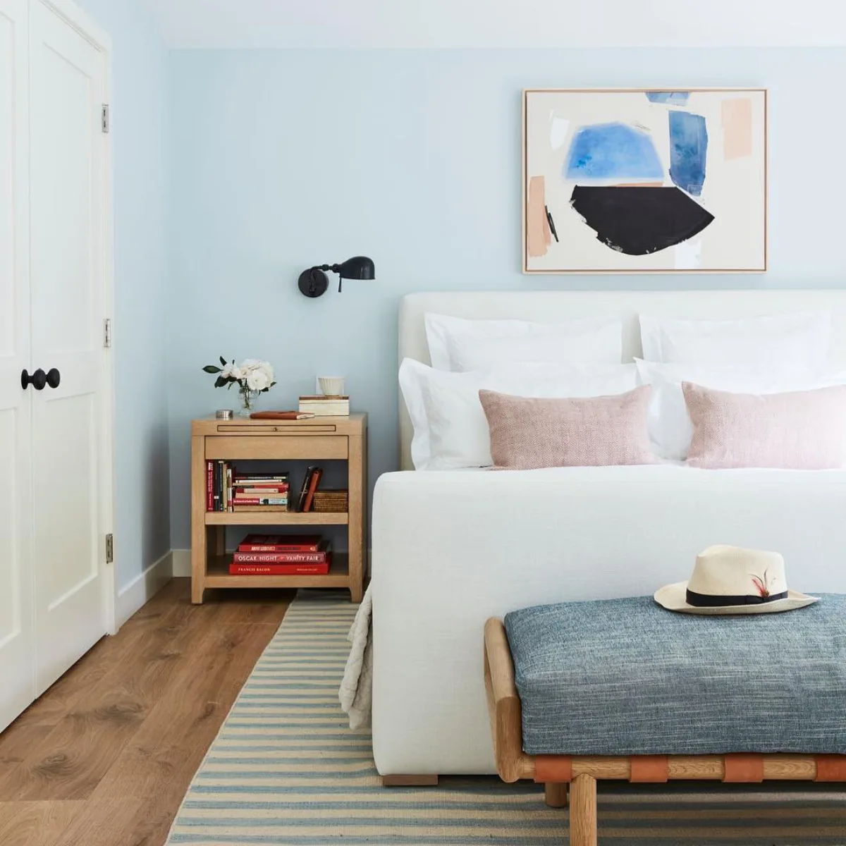 Interior kamar tidur modern dengan cat dinding warna biru muda langit (light blue) yang cerah dipadukan dengan tempat tidur putih minimalis.