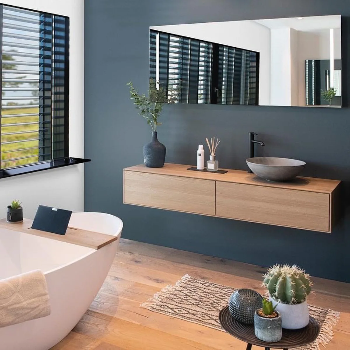 Interior bergaya modern kontemporer dengan warna cat dinding abu-abu arang (charcoal grey) yang gelap namun elegan dipadukan dengan furnitur kayu.