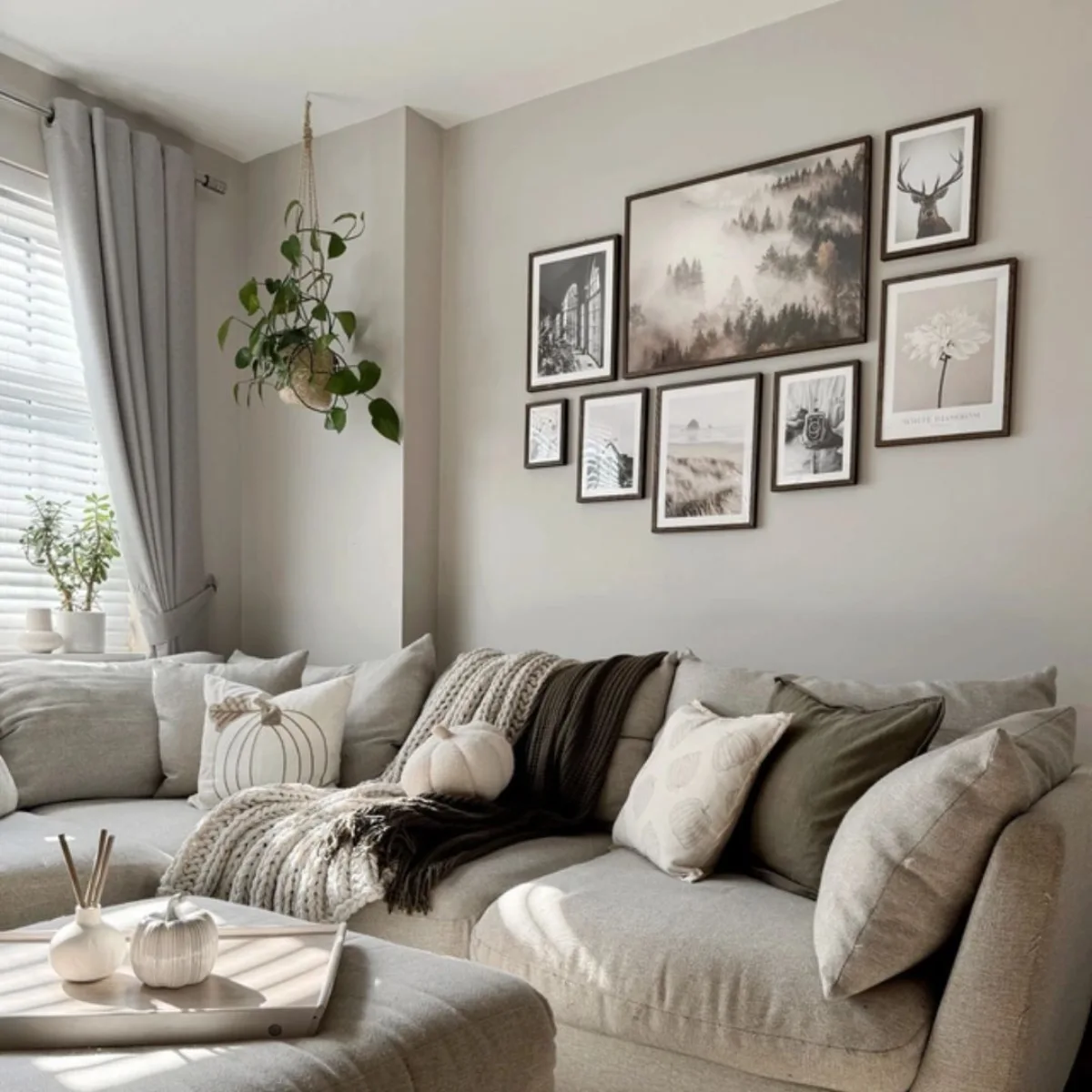 Ruangan yang hangat dan nyaman dengan warna cat dinding greige (perpaduan abu-abu dan beige) serta galeri foto dinding monokrom.