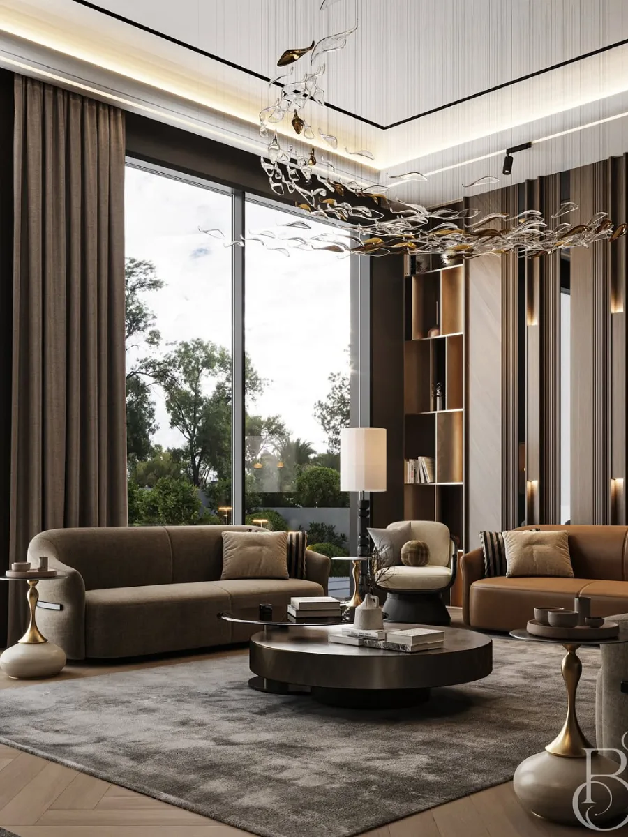 Tampilan perspektif samping dari ruang tamu mewah yang luas dengan jendela kaca besar setinggi plafon yang memperlihatkan pemandangan taman hijau. Ruangan dilengkapi furnitur bernuansa earthy tone, karpet abu-abu besar, dan instalasi lampu gantung kristal yang melengkung elegan.