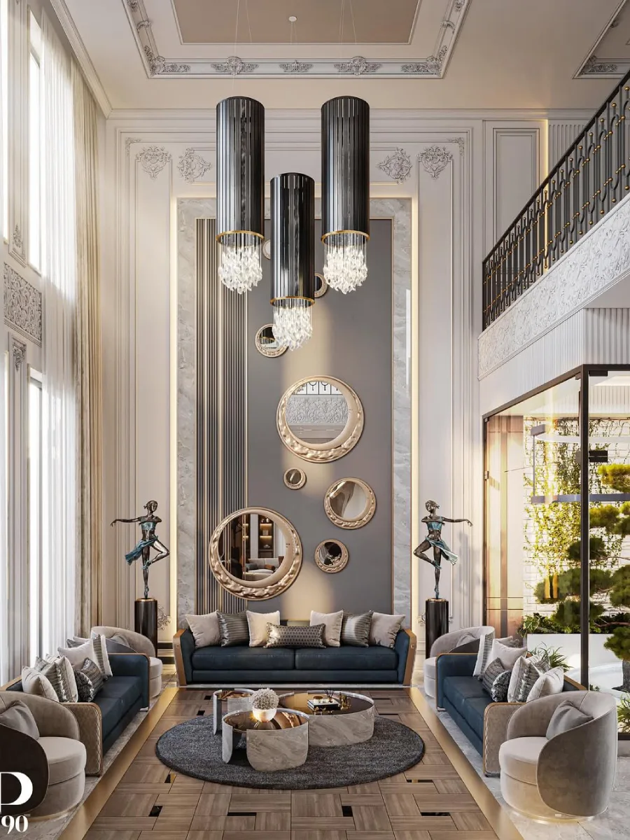 Ruang tamu bernuansa neo-klasik modern yang simetris. Dinding utama dihiasi oleh susunan cermin bulat berbagai ukuran di atas panel abu-abu. Terdapat dua patung penari perunggu yang mengapit sofa biru navy mewah, serta lampu gantung silinder hitam dengan untaian kristal di bawahnya.