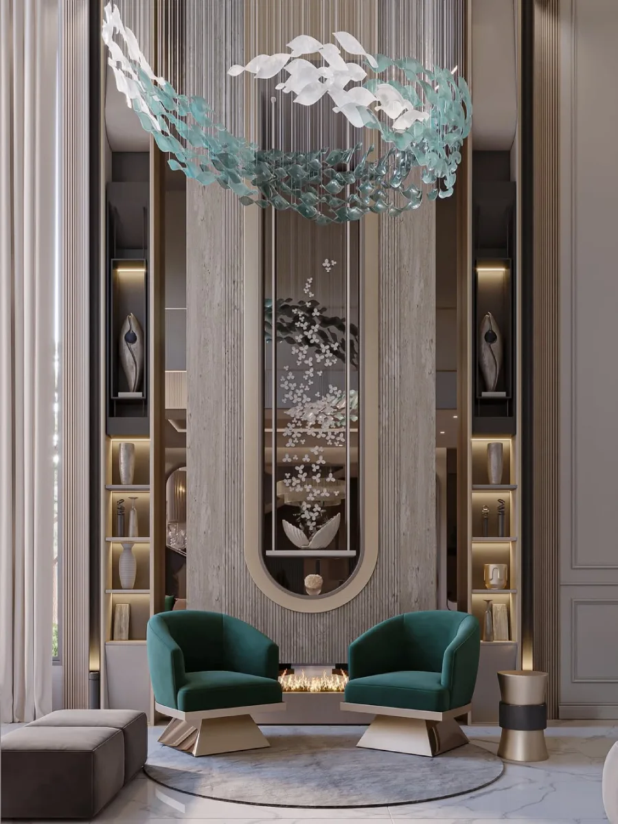 Detail sudut ruangan mewah yang menonjolkan dua kursi armchair beludru hijau zamrud dengan kaki logam emas. Di belakangnya terdapat partisi kaca dengan detail hiasan bunga putih yang menjuntai vertikal dan lampu gantung artistik berwarna biru transparan yang menyerupai kelopak bunga.