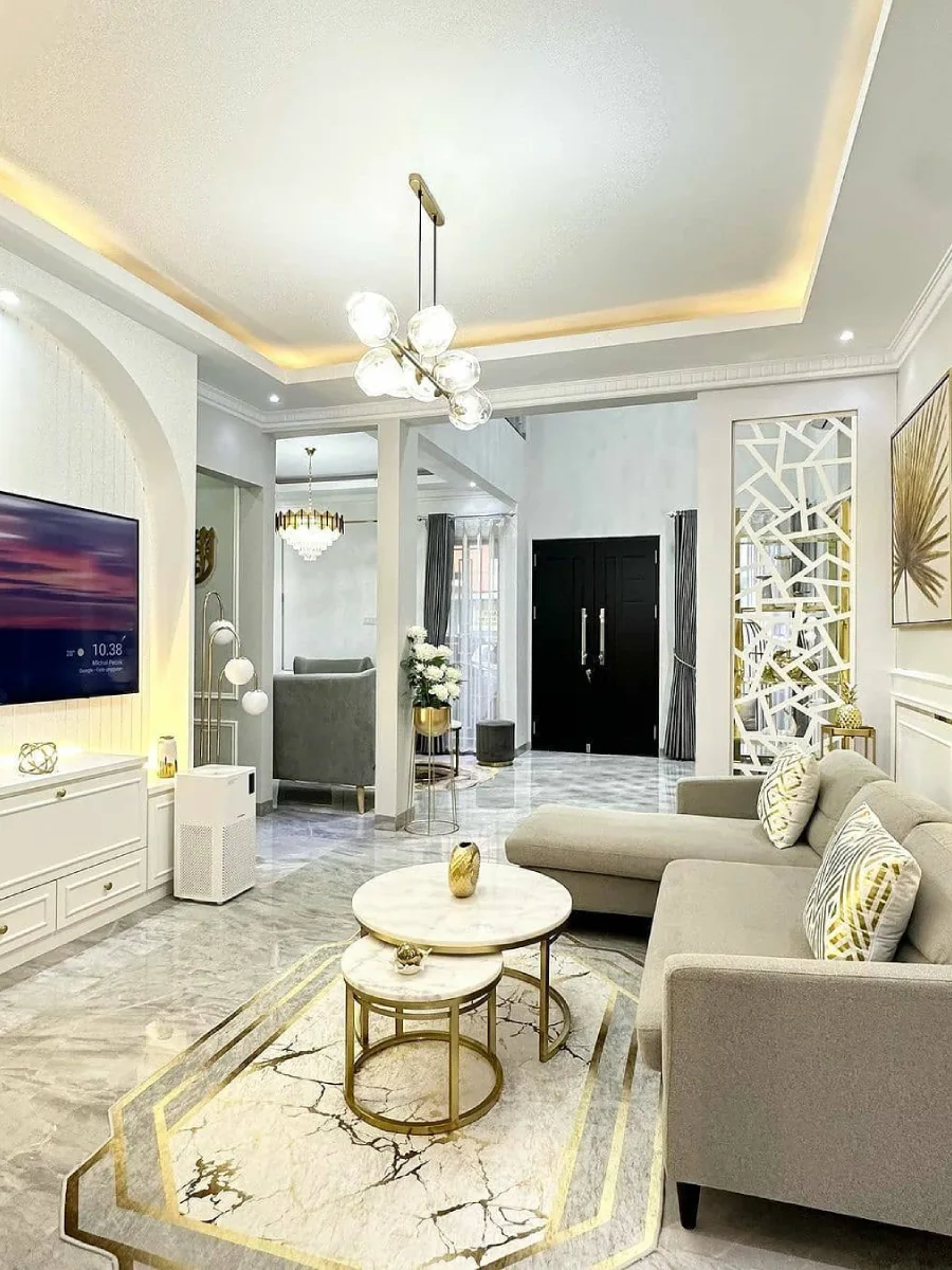 Interior ruang tamu modern dengan partisi geometris putih, lampu gantung bola, dan pintu utama hitam yang memberikan kesan kontras.