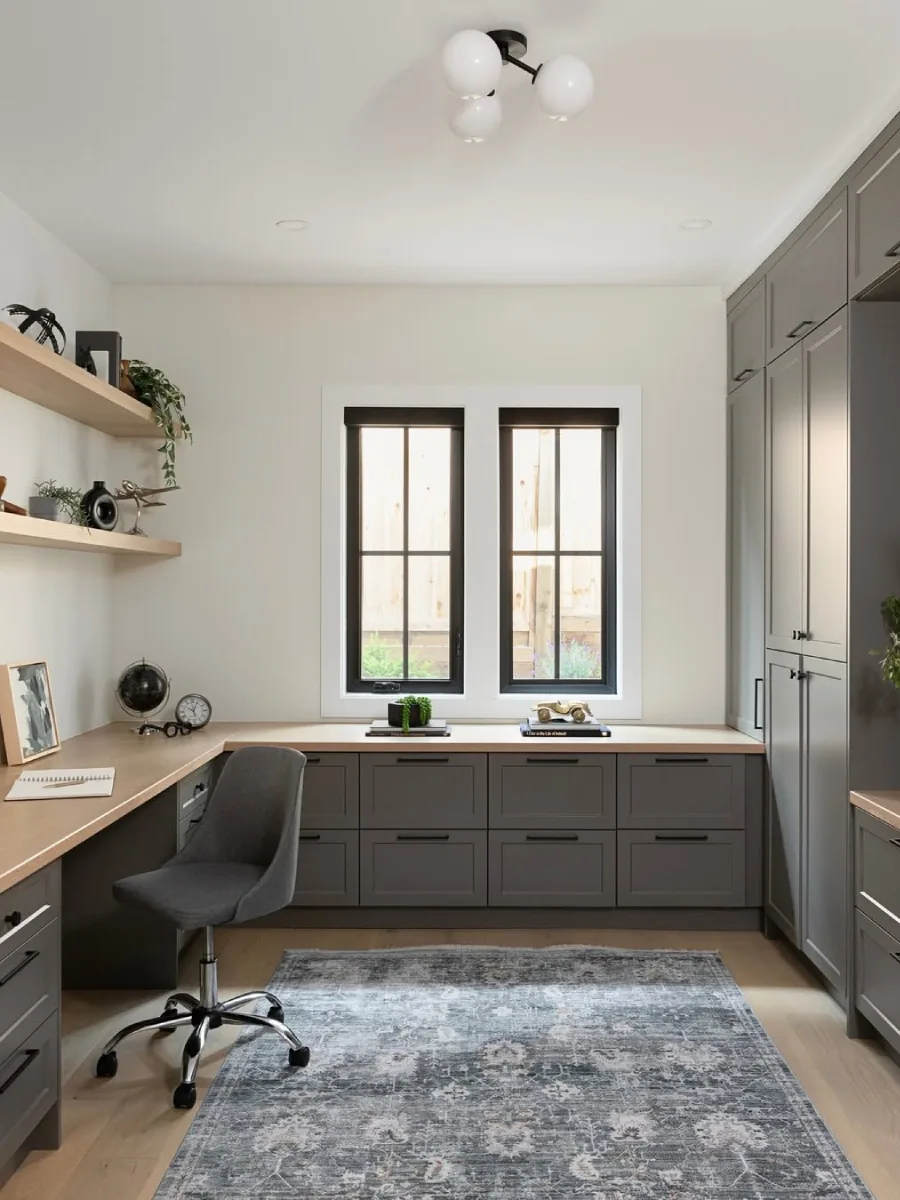 Inspirasi ruang kerja sudut bentuk L dengan kabinet dan lemari penyimpanan berwarna abu-abu gelap (charcoal), kursi kerja abu-abu, dan jendela ganda.