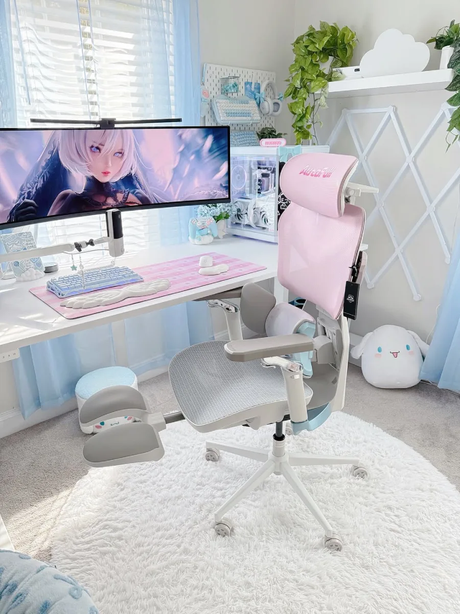 Fokus pada kursi gaming merek AutoFull berwarna pink dan abu-abu muda dengan sandaran kaki yang sedang ditarik keluar, berada di depan meja kerja estetik berdinding tirai biru muda transparan.
