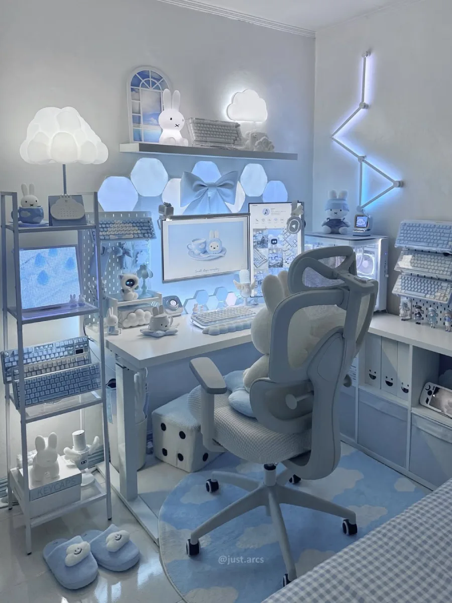 Ruang kerja bertema baby blue yang sangat imut dan terkonsep. Dilengkapi lampu dinding heksagonal, dekorasi pita biru raksasa, lampu berbentuk awan, koleksi boneka kelinci Miffy, dan rak putih yang penuh dengan keyboard serba biru.