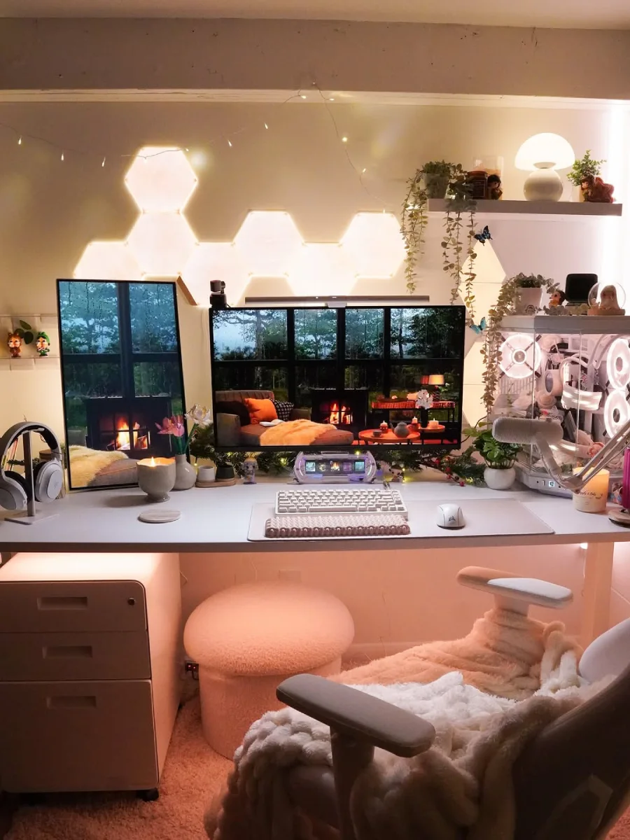 Tampak depan meja kerja estetik dengan pencahayaan hangat yang menenangkan. Di atas meja putih rapi terdapat monitor berlayar lebar, keyboard dan mouse putih, serta PC case dengan lampu kipas warm white. Di kolong meja terdapat kursi sandaran kaki bundar berbahan fleece.