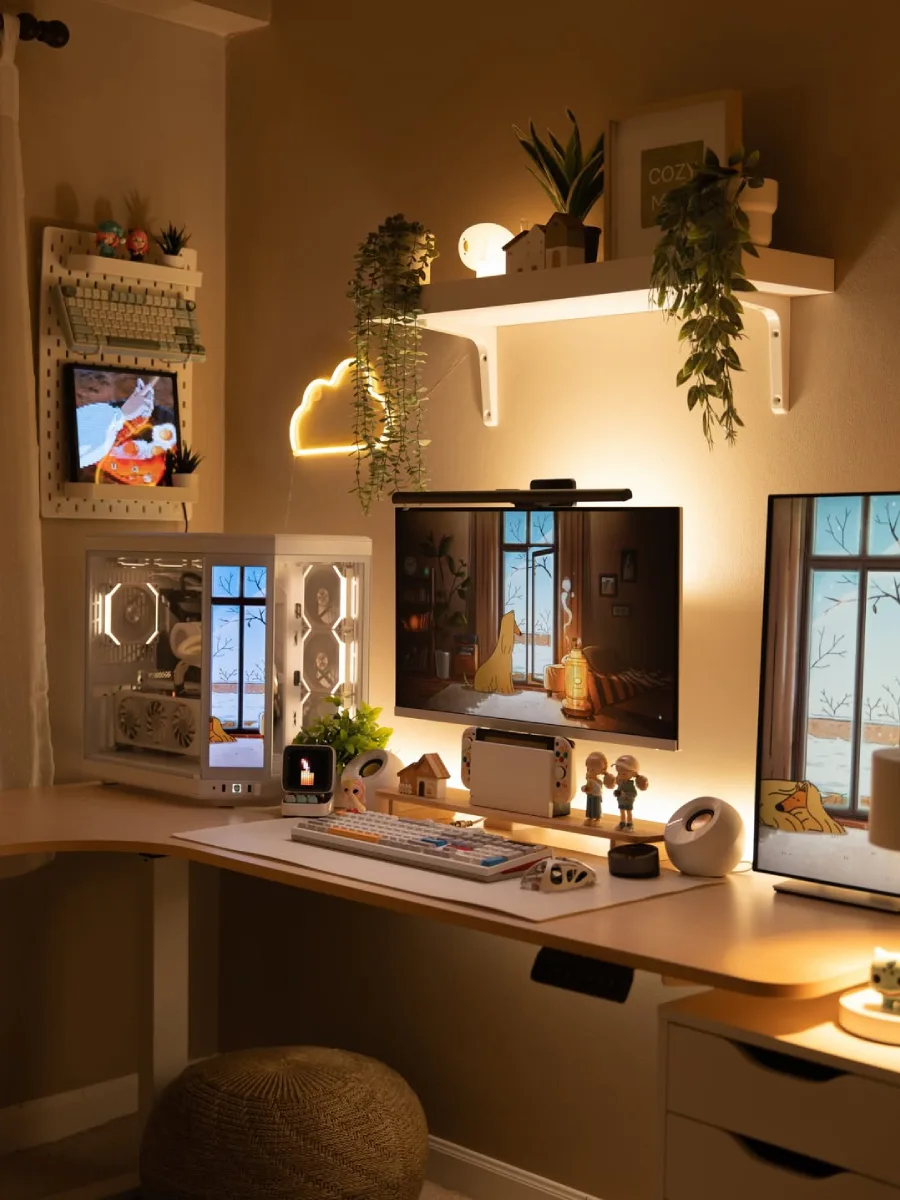 Suasana meja kerja yang nyaman dengan layar monitor menampilkan animasi ruangan musim dingin, dilengkapi rak ambalan dinding dengan tanaman rambat dan pencahayaan kuning hangat yang cozy.
