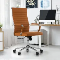 Kursi kerja cokelat modern dengan roda dan sandaran tinggi di ruang home office minimalis berwarna putih, lengkap dengan meja kayu dan komputer desktop.