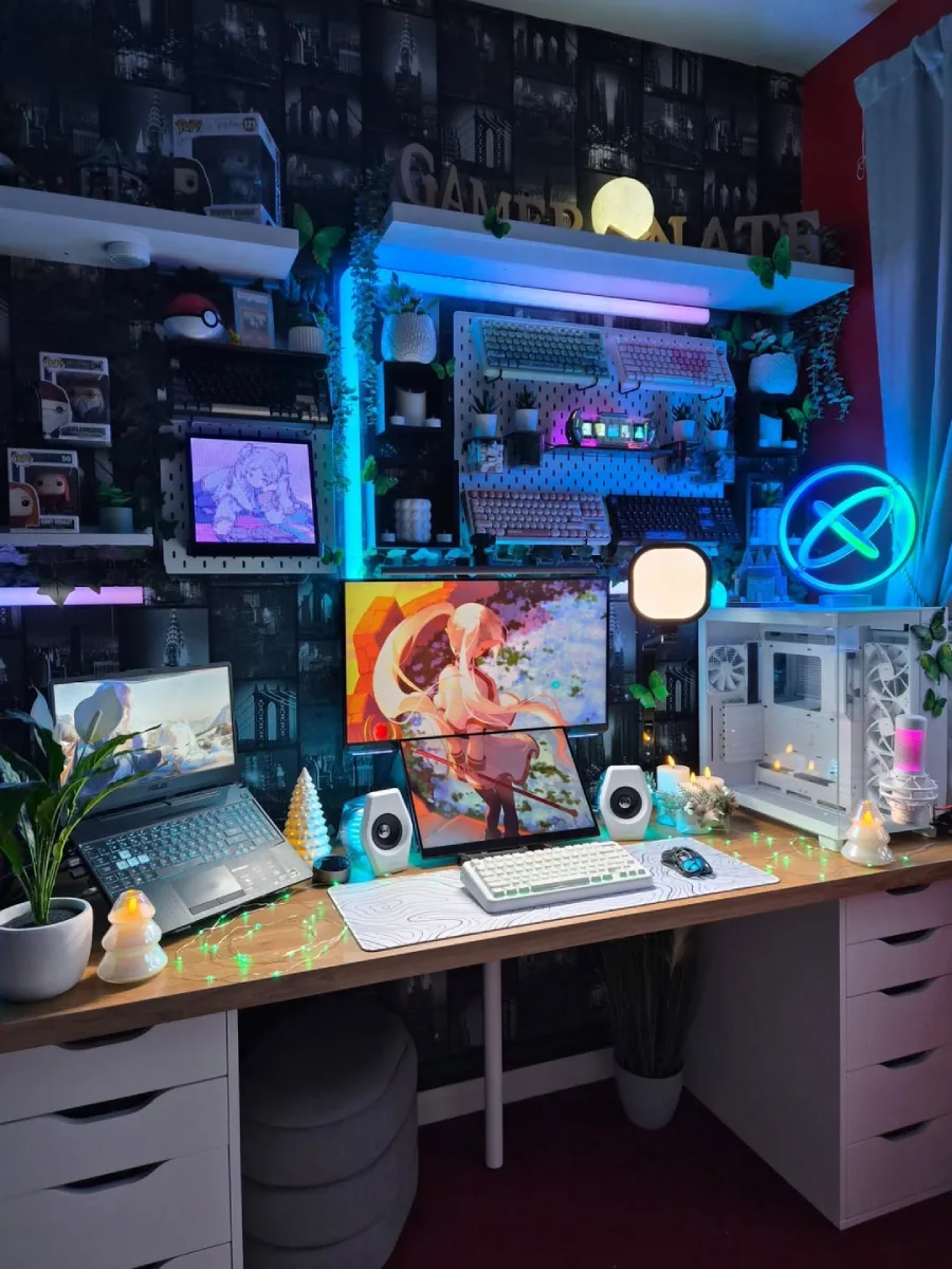 Setup meja komputer bernuansa cozy dan ramai dengan meja kayu. Terdapat laptop di sebelah kiri, dua monitor bertumpuk di tengah dengan wallpaper anime, lampu neon ring biru, tanaman rambat buatan, pajangan Funko Pop, dan pegboard putih penuh aksesoris.