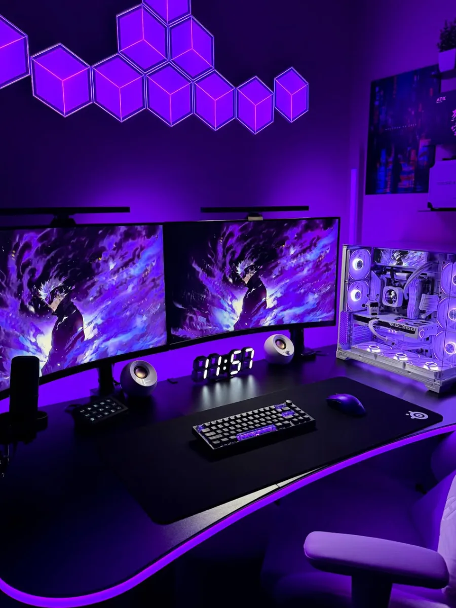Setup PC gaming bernuansa lampu ungu pekat. Menampilkan dua monitor dengan wallpaper karakter anime bernuansa ungu, casing PC putih dengan pencahayaan ungu, jam meja digital, tepi meja menyala, dan lampu dinding heksagon berwarna ungu.