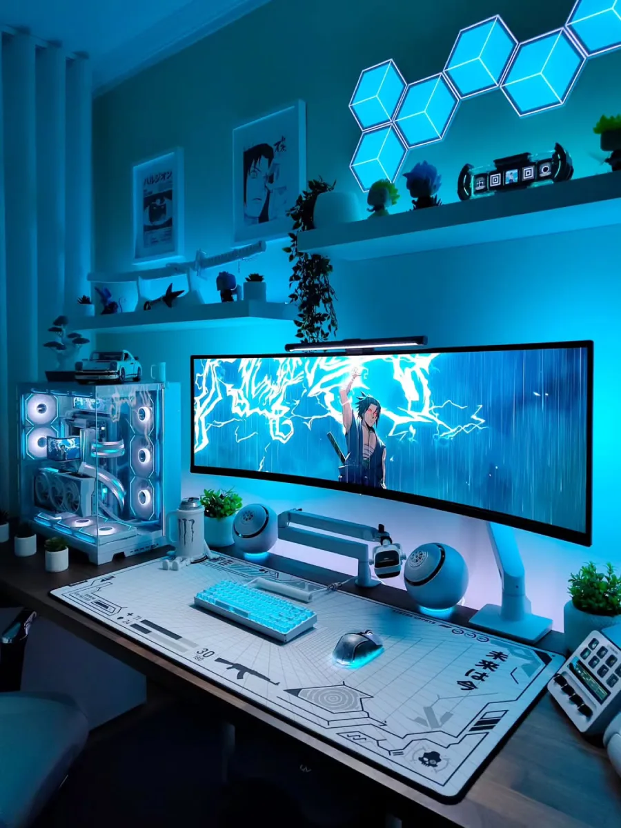 Setup PC bernuansa biru cyan terang. Menampilkan satu layar monitor super ultrawide melengkung dengan wallpaper anime Sasuke. Dilengkapi casing PC putih, sepasang speaker berbentuk bulat unik, desk mat putih bermotif blueprint, dan lampu dinding heksagonal biru.