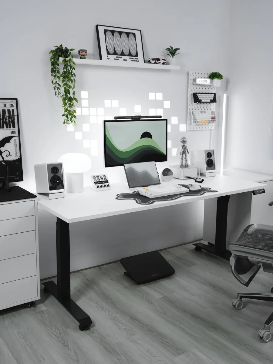 Desain home office minimalis modern serba putih dengan standing desk, monitor ganda, dan lampu dinding geometris yang estetik.