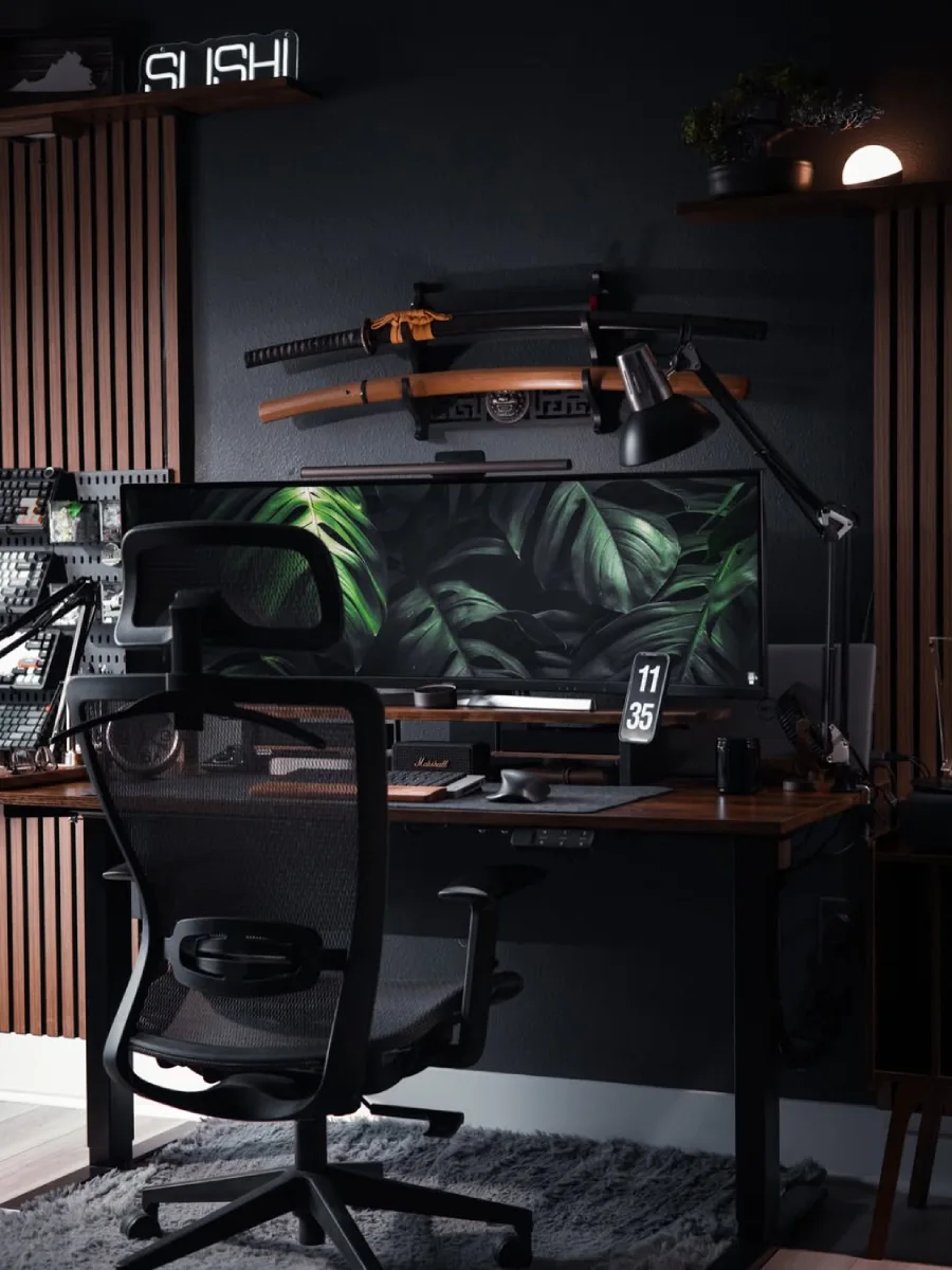 Inspirasi ruang kerja estetis bernuansa hitam pekat dengan aksen panel kayu vertikal, dekorasi pedang katana di dinding, kursi jaring hitam, dan lampu neon kecil.