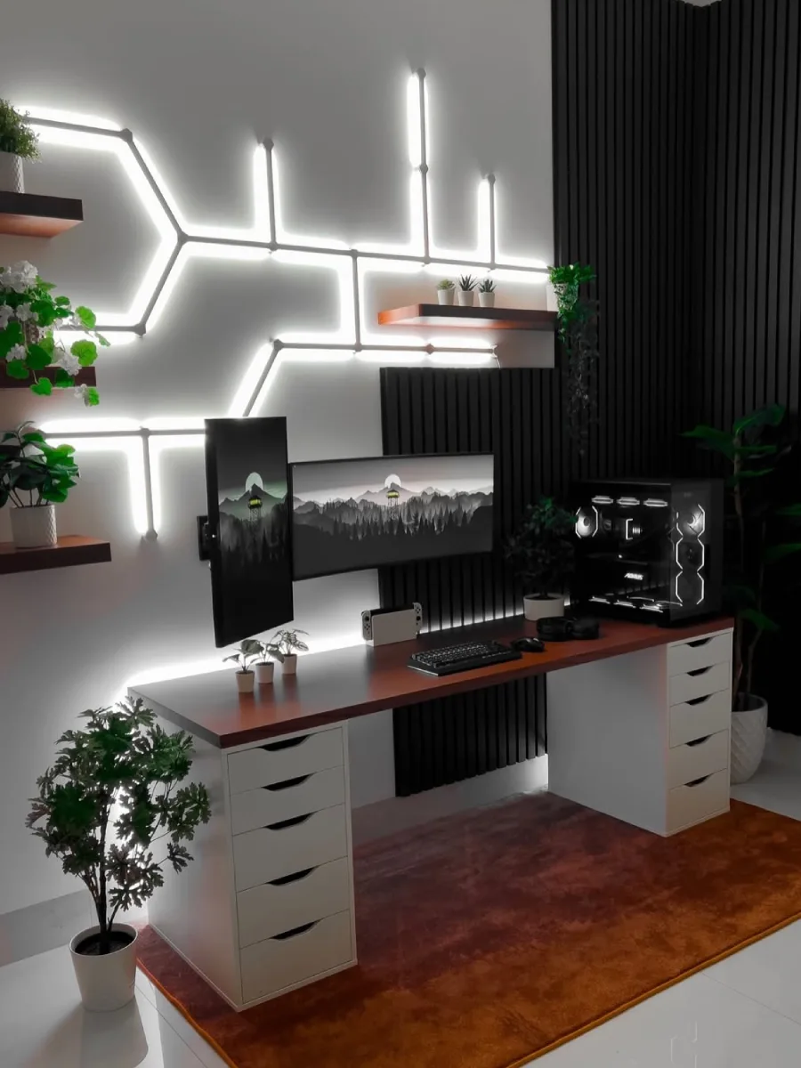 Desain ruang kerja futuristik dan terang dengan dekorasi lampu neon geometris di dinding, laci meja putih minimalis berdaun meja kayu, dan setup dua monitor beresolusi tinggi.