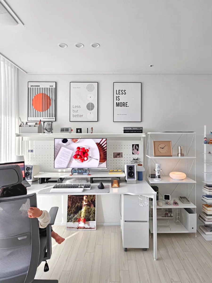 Desain home office minimalis modern bergaya Skandinavia bernuansa putih bersih (all-white), dilengkapi rak terbuka dan hiasan dinding poster tipografi.